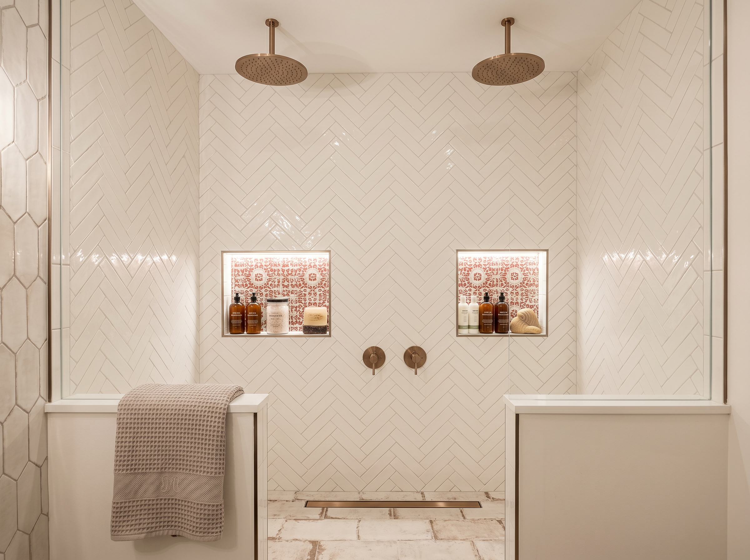 Floor-to-ceiling herringbone tile shower with frameless glass and niche — luxury master bath — May Construction